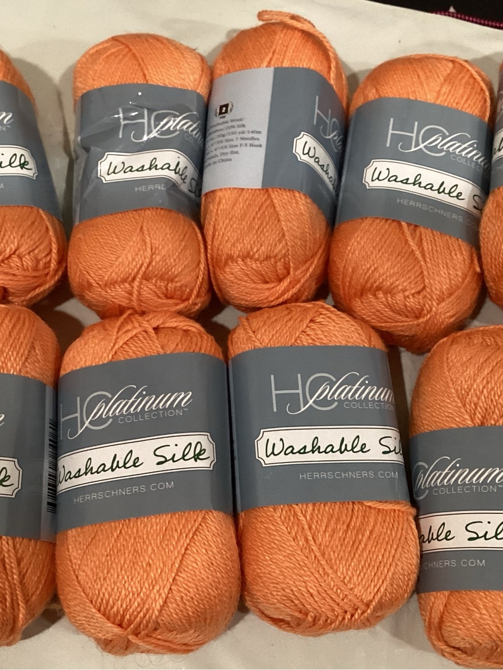 9 hanks of Herschners platinum washable silk yarn in coral colorway